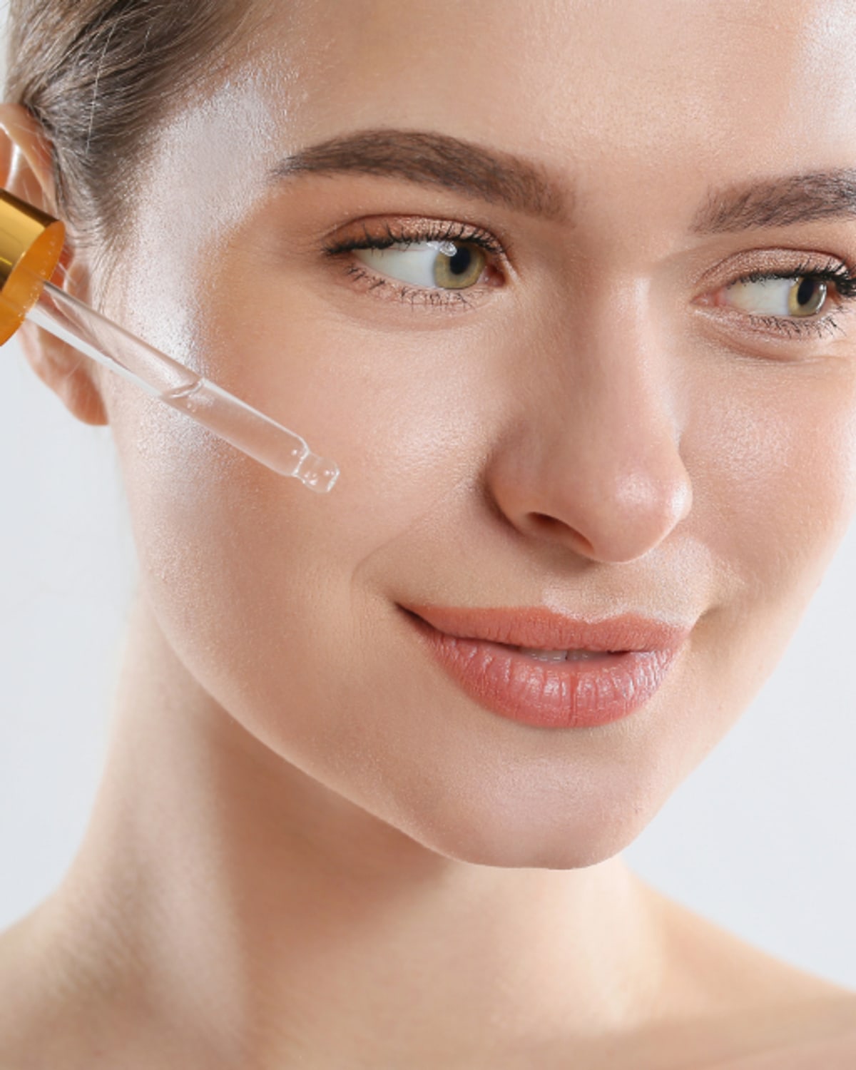 Woman using a hydrating serum beside a humidifier